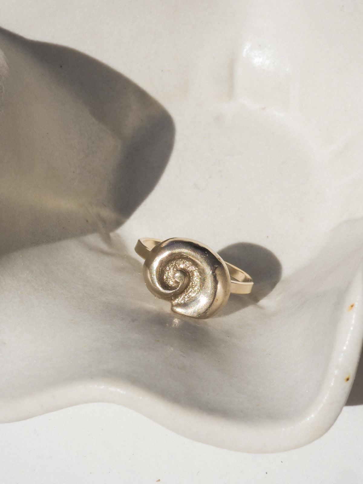 Gold spiral ring on a textured white surface
